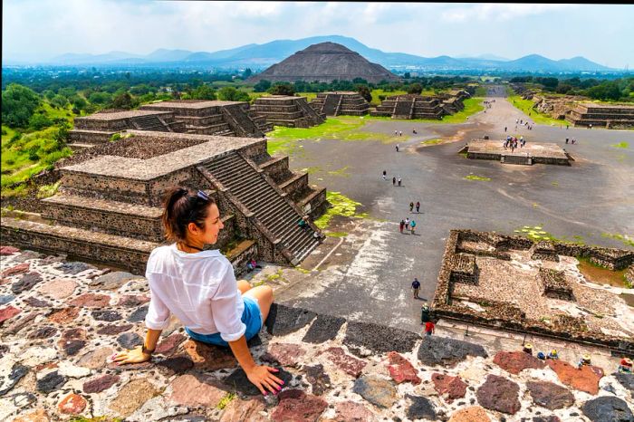 A woman perches atop a pyramid at the ancient site of Teotihuacán, Mexico