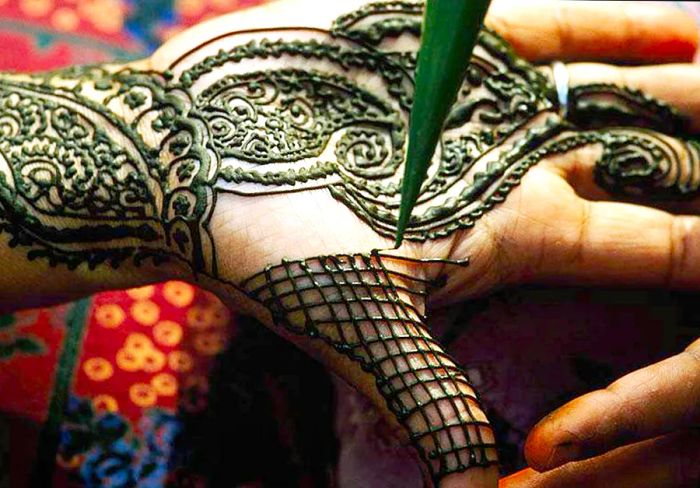 An artist applying a henna design on a woman's hand in Dubai.