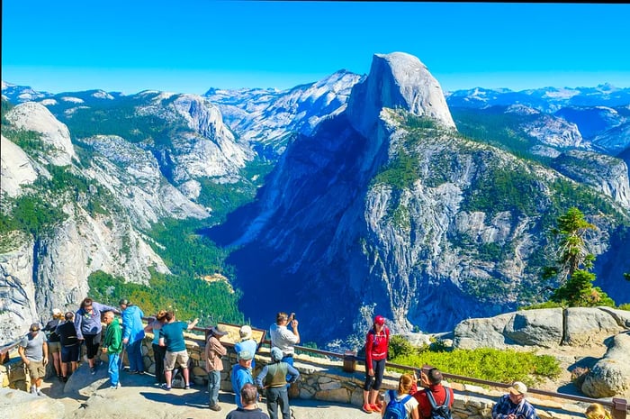 Visitors gather at Glacier Point, framed by the iconic Half Dome mountain.