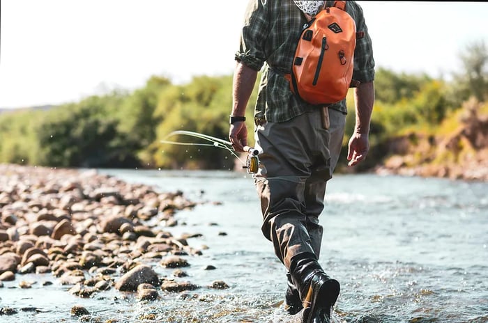 A man wading through a river while fly fishing in Wyoming, USA