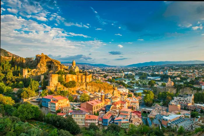 A historic city with a church atop a hill, cascading down towards contemporary buildings by the river