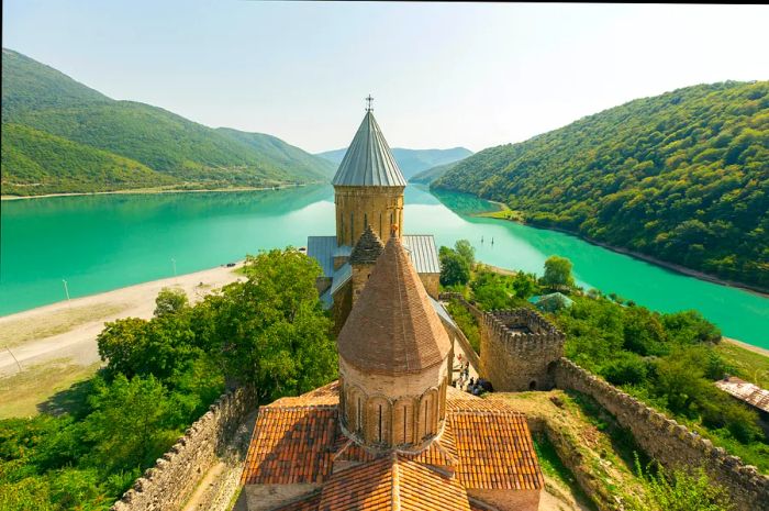 A view from the top of a turreted castle overlooking a lush green lake