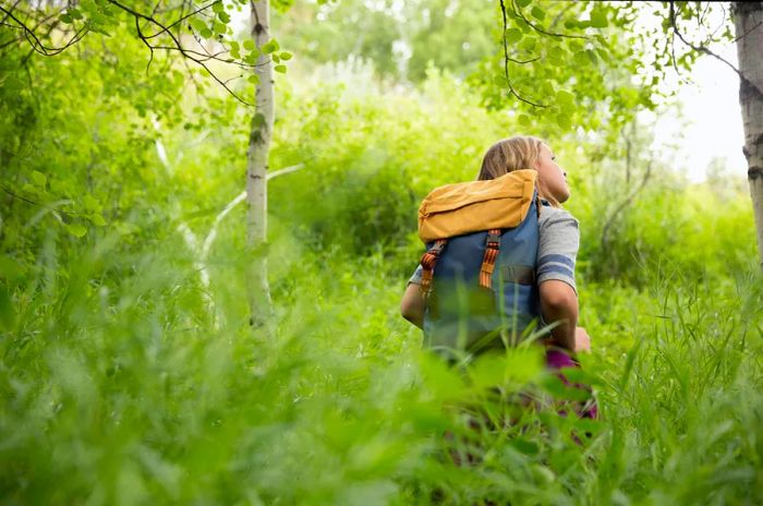 A young woman with a backpack takes in the sounds of the forest around her; Quiet parks.