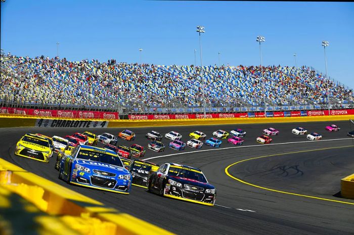 A racetrack bustling with speeding cars and packed stands. Jimmie Johnson (48) and Austin Dillon (3) lead the pack during the Bank of America 500 at Charlotte Motor Speedway in Concord.