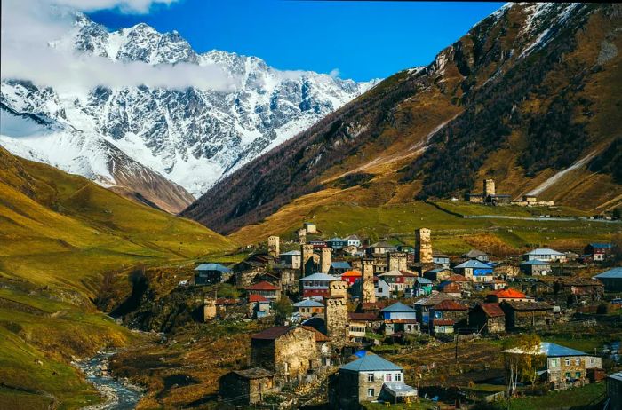 A secluded mountain village nestled amidst steep hills and mountains, featuring a variety of unique buildings including distinctive stone towers.