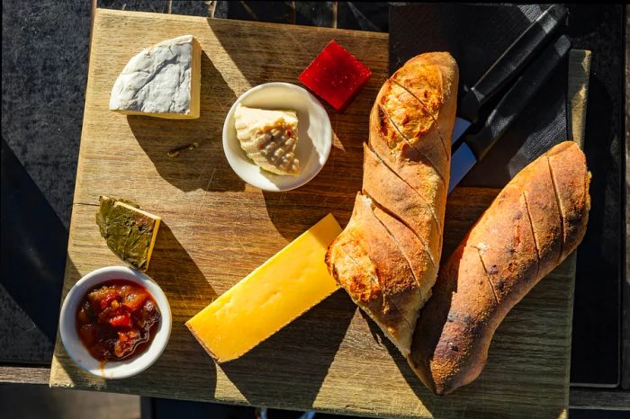 An outdoor picnic featuring a cheese and bread platter on a sunny day at Bruny Island, Tasmania.