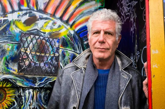 Anthony Bourdain in front of a vibrant mural in the Lower East Side of New York City