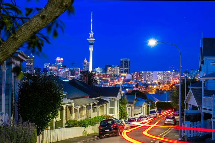 Light Trail Street in Ponsonby, an inner-city suburb of Auckland, illuminated at dusk, with the city center and the Sky Tower in the background.