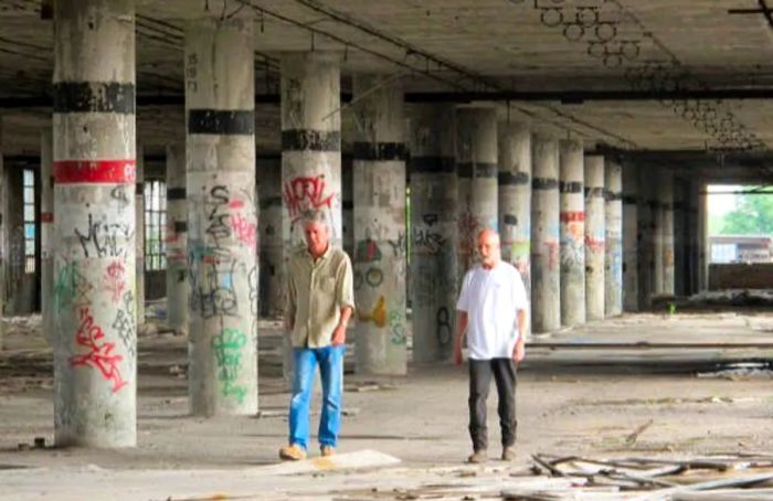 Anthony Bourdain traversing an abandoned structure alongside another man in Detroit.