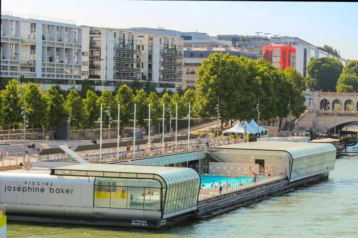 A floating open-air swimming pool complex on the edge of a river.