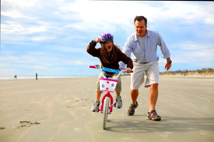 A father and daughter cycling along the sandy shores of Kiawah Island, South Carolina