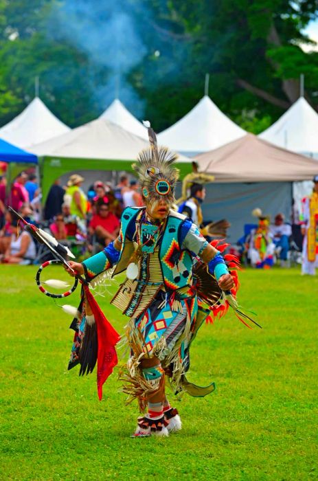 A young boy adorned in traditional attire, complete with colorful beads and feathers, performs during the Summer Solstice Indigenous Arts Festival in Ottawa.