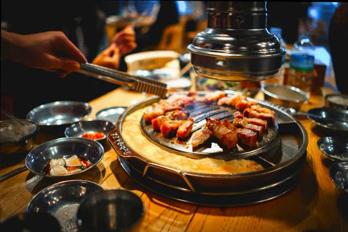 A diner uses chopsticks to grab meat sizzling on the grill at a barbecue restaurant in Seoul, South Korea.