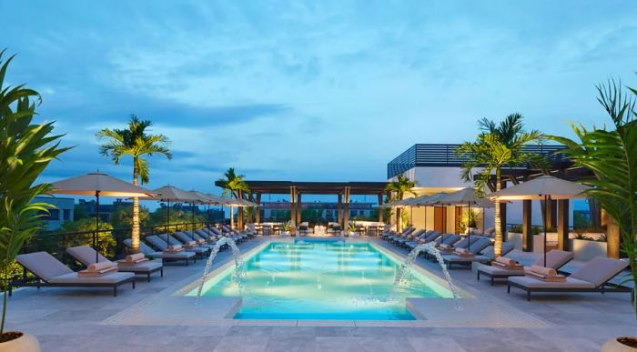 Sun loungers surround a chic rooftop pool, illuminated by soft blue lighting.