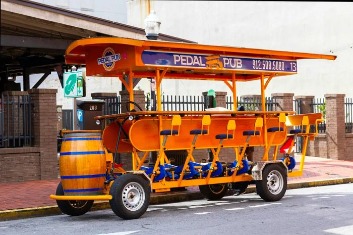 Charming empty Pedal Pub bus parked on the street in the popular City Market area of Savannah