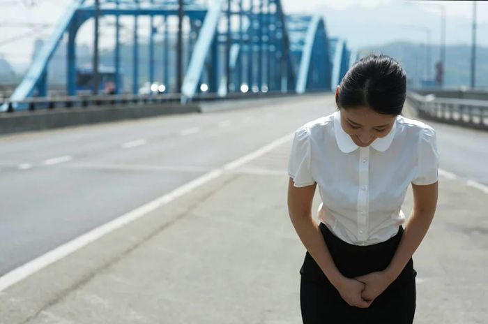 A businesswoman bows on a bridge in Gangnam, Seoul, South Korea