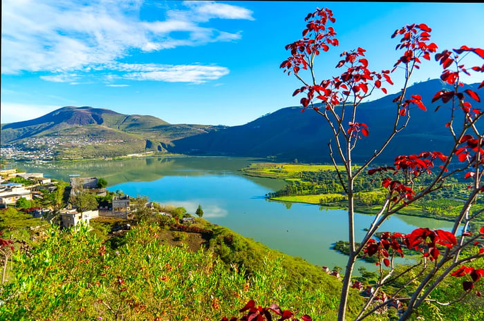 A picturesque view of a lake with a few quaint structures nestled in the hills around it