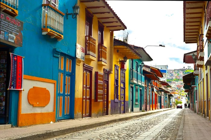 A vibrant line of colorful houses and shops along a cobbled street.