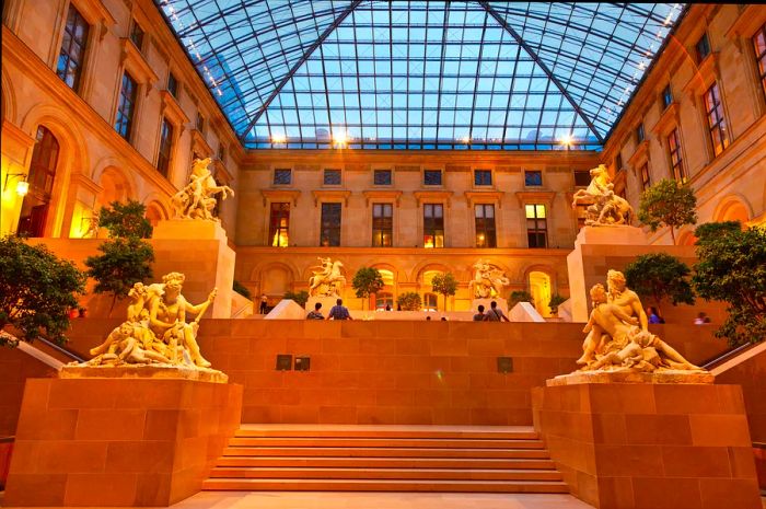 Visitors admire the sculptures in the Cour Marly, a spacious atrium topped with a massive glass ceiling within the Louvre in Paris.