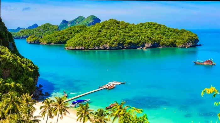 A boat glides past a small island lush with greenery