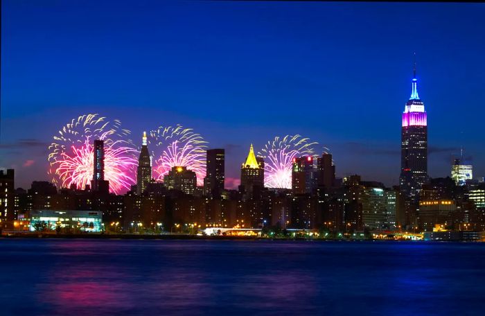 The New York City skyline (featuring the Empire State Building) illuminated with fireworks on the Fourth of July night.