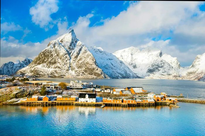 Traditional Rorbu huts nestled against clear blue waters and mountains in Sakrisøy.