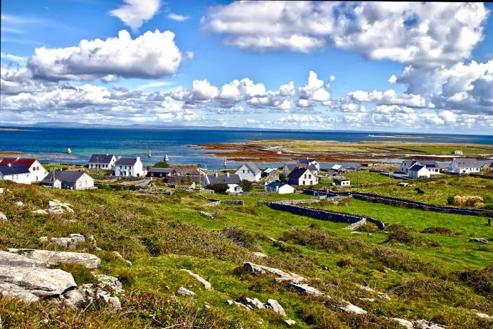 A row of white coastal cottages nestled beside a windswept beach