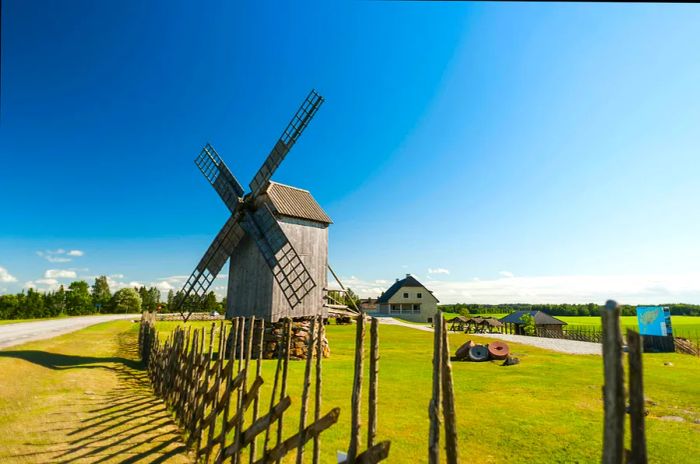 A traditional wooden windmill set against farmland.