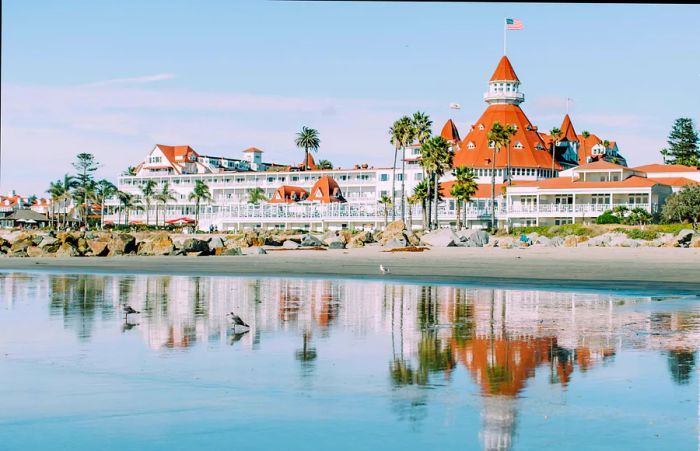 A coastal hotel with a grand white facade, red roofs, and palm trees