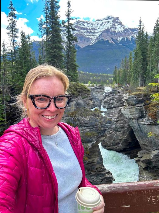 A woman with a waterfall behind her: Melissa Yeager at Athabasca Falls