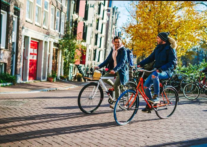 Two cyclists riding through a street in central Amsterdam, Netherlands