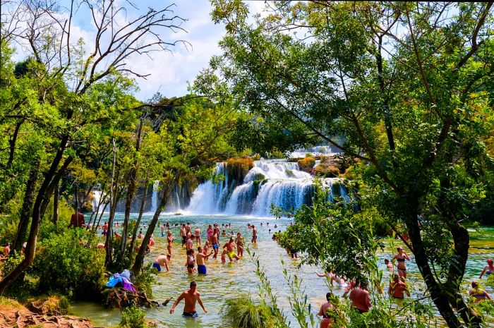 Visitors enjoy the refreshing pools beneath the waterfalls in Krka National Park, Croatia, Europe.