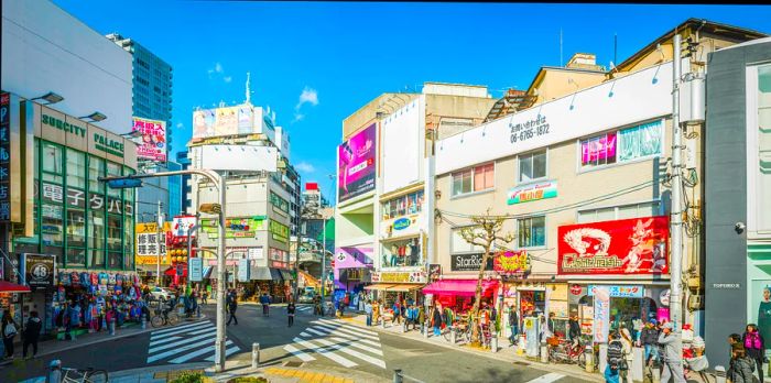 People navigate a bustling intersection filled with shops and restaurants in the city.