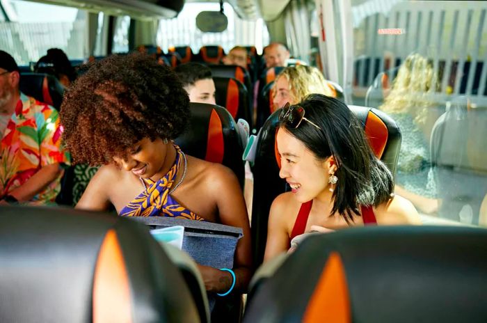 Two women aboard a bus filled with tourists in Ecuador, looking thrilled