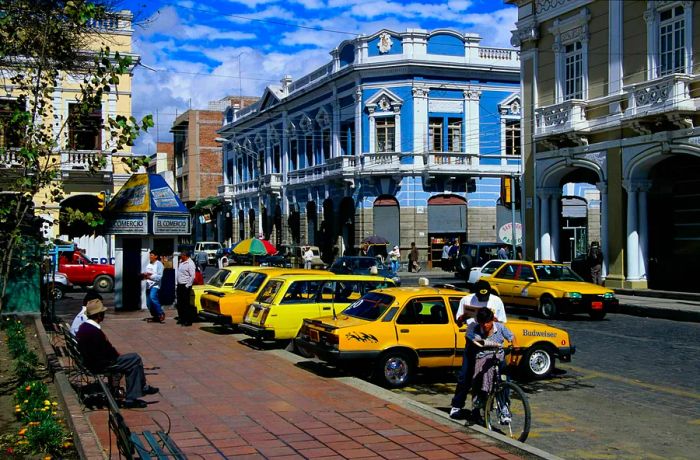 A row of yellow taxis parked along the sidewalk in Riobamba, Ecuador.