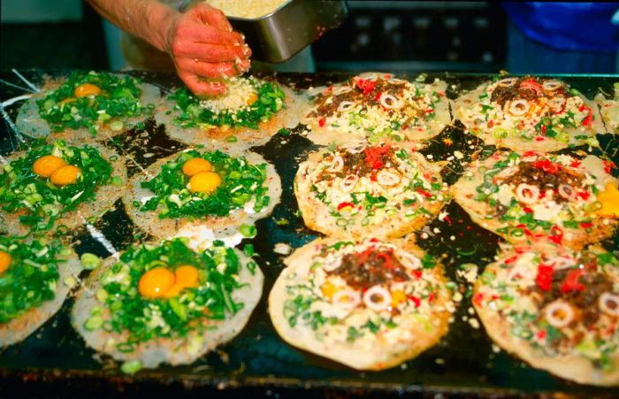 A chef crafting savory cabbage-based omelettes on a hot plate.