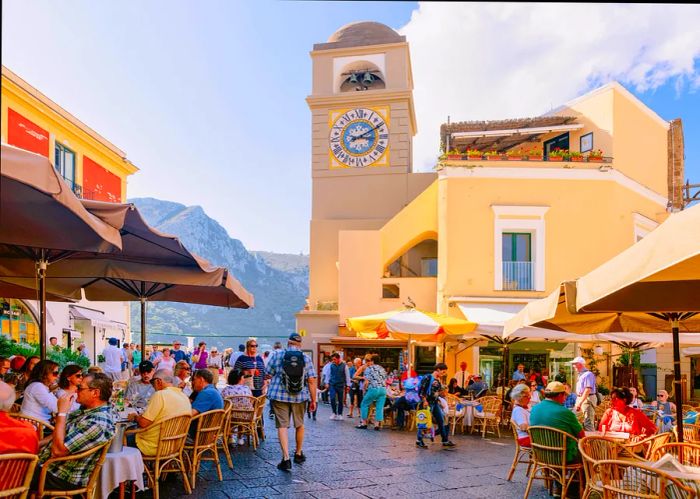 Visitors at Piazza Umberto I Square, featuring the Church of Santo Stefano in the historic center of Capri Island, Naples, Italy.