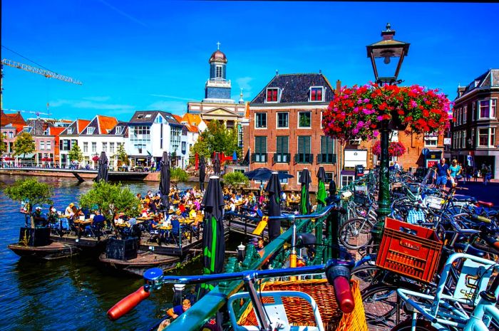 Individuals enjoying drinks on a floating barge in a canal in central Leiden, South Holland, Netherlands