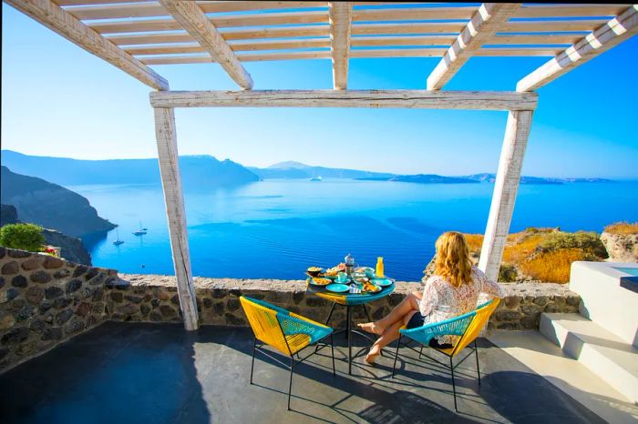 A woman enjoying breakfast with a stunning view of Santorini