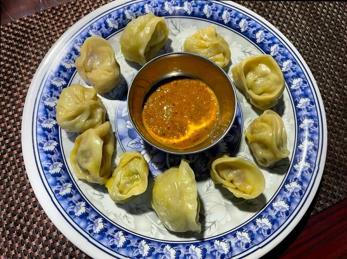 A plate of small white dumplings encircling a bowl of dipping sauce