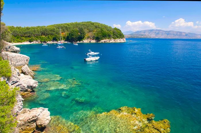 A few small boats are anchored in a bay with crystal-clear turquoise waters.