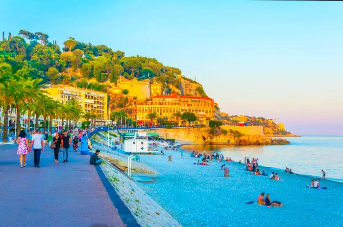 Visitors enjoying a stroll along the Promenade des Anglais in the late afternoon light.