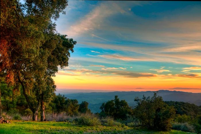 A stunning sunset casts its glow over hills that fade into the misty horizon as daylight wanes.