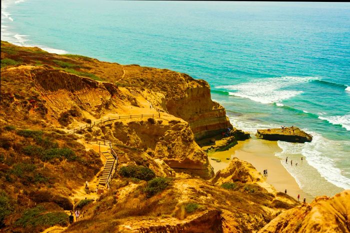 A rugged cliff extending into the ocean, featuring a boardwalk that meanders through the headland