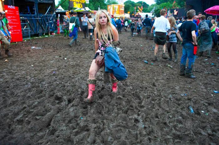 A woman wading through thick mud in wellies