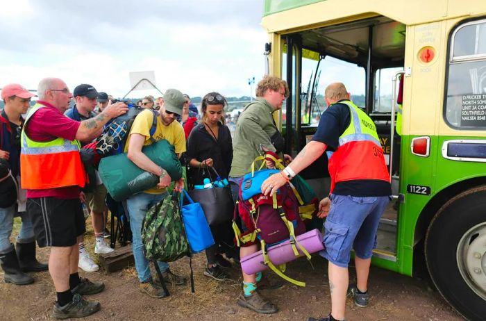 Festival-goers are assisted onto a bus by staff at the conclusion of a music event.