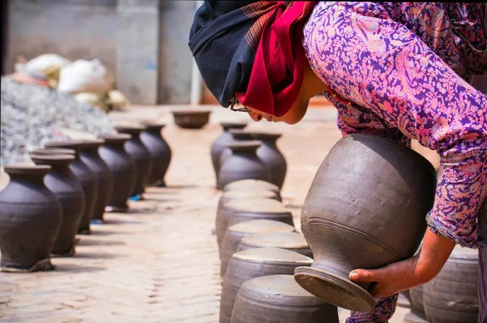 A Nepalese artisan drying a raw clay pot in her workshop, Madhyapur Thimi, Bhaktapur District, Nepal