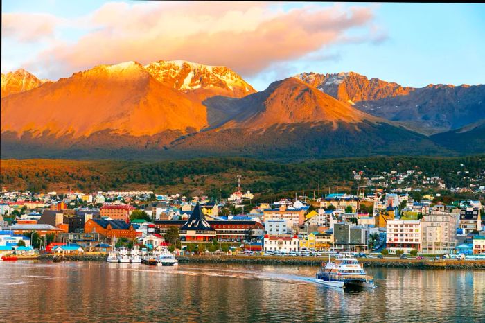 Boats depart from a port set against a backdrop of mountains