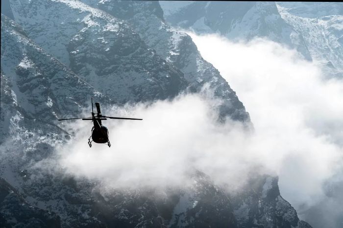 A helicopter soars among low clouds above the Annapurna Himalayas in Nepal.