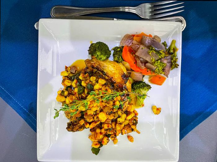 A dish of roasted chicken accompanied by corn and poblano salsa